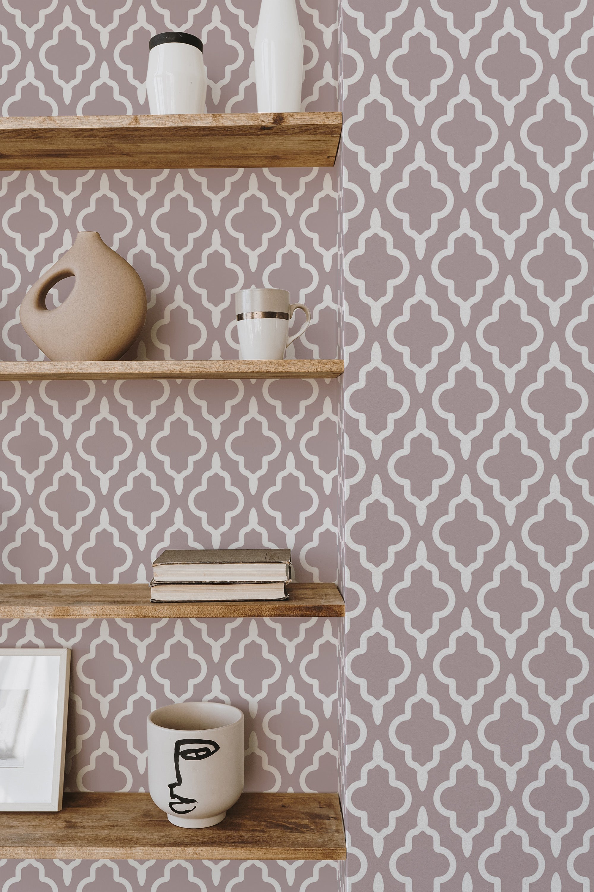 Self-adhesive wallpaper with a repeating geometric quatrefoil pattern in gray and white tones, flanked by wooden shelves with assorted decorative items.