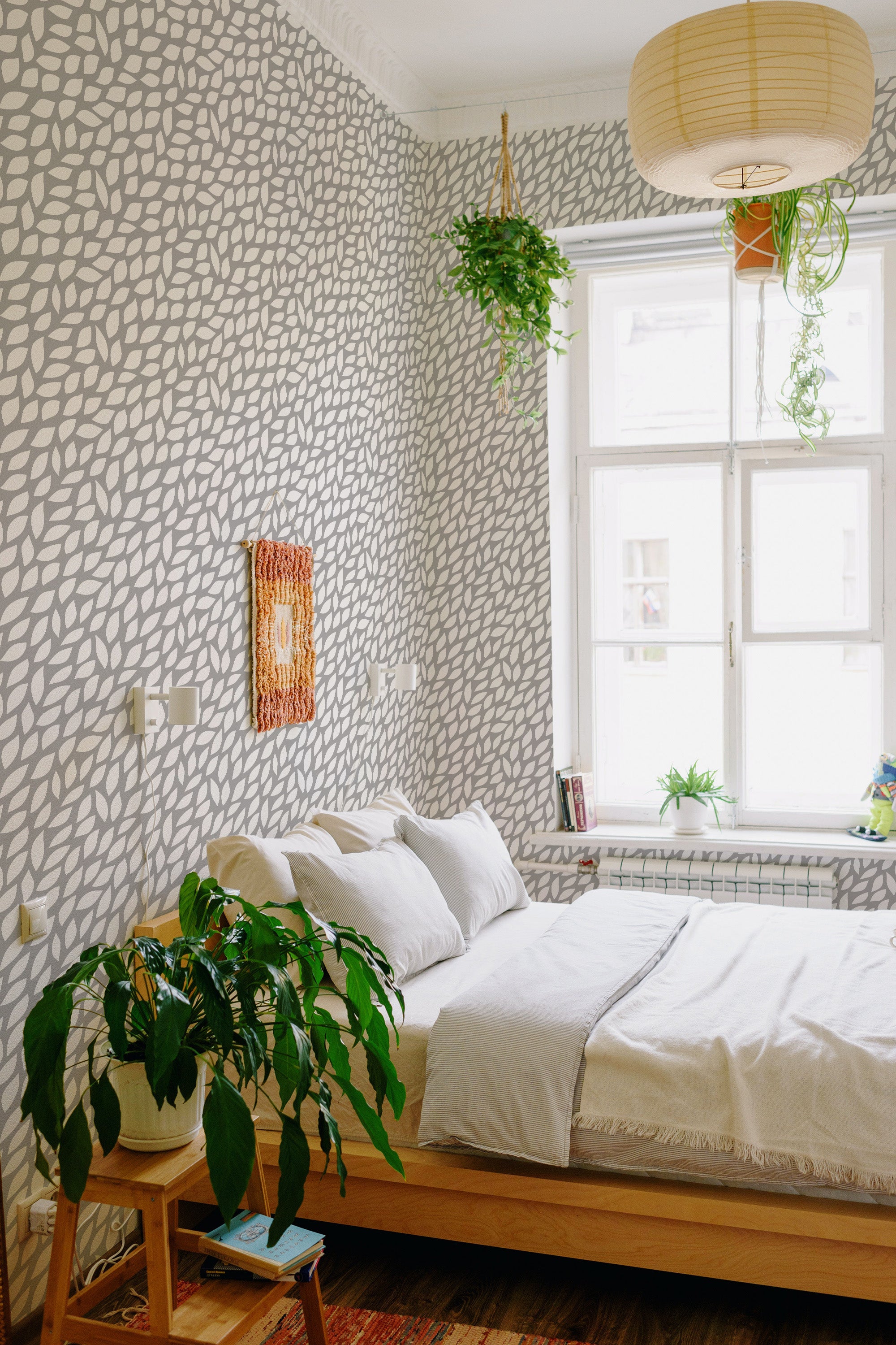 A room with a Leaf print wallpaper design that covers the walls. The pattern is made up of white leaves against a grey background, offering a subtle and natural aesthetic. Traditional wallpaper.