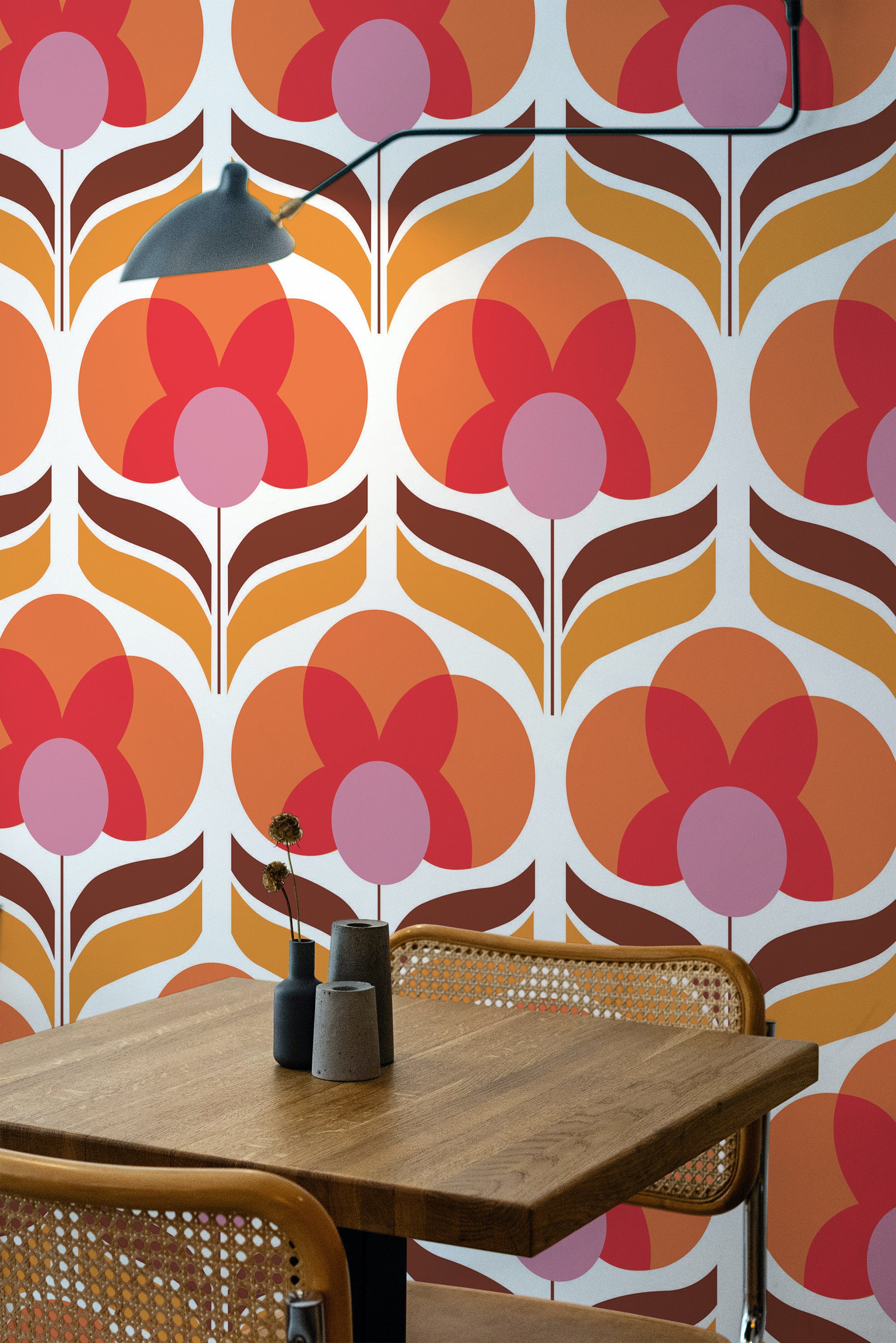 Self-adhesive wallpaper with a bold Retro flower pattern in shades of orange, pink, and white, accentuating a modern room with a wooden table and chairs.