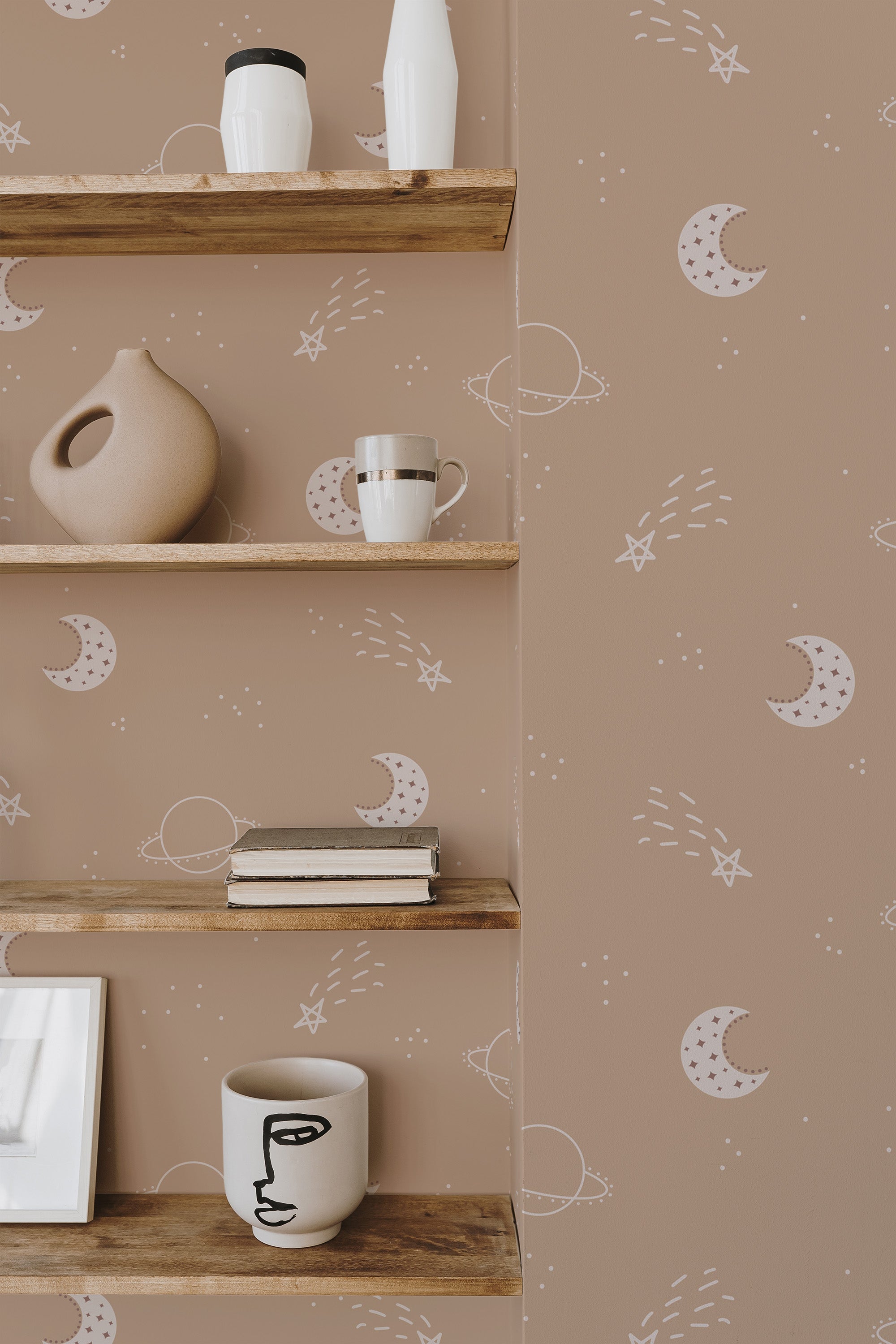 Self-adhesive wallpaper with a minimalist celestial design including crescent moons, stars, and abstract lines on a neutral background, partially obscured by wooden shelves with decorative items.