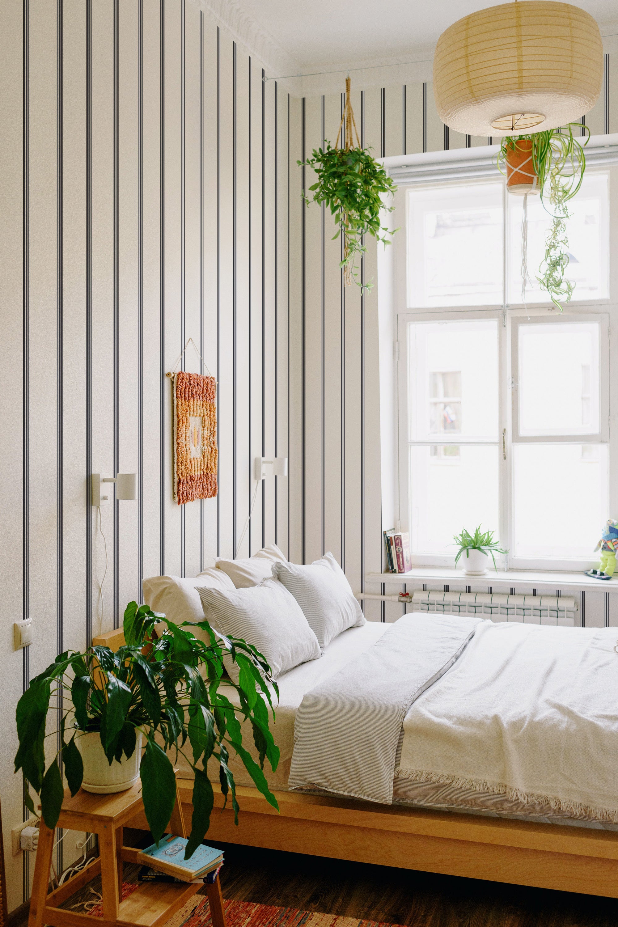 A room with wallpaper that has vertical stripes in varying shades of soft grey and cream, creating a subtle and calming contrast. The pattern adds height and elegance to the space, giving a classic, timeless feel to the room. Traditional wallpaper.