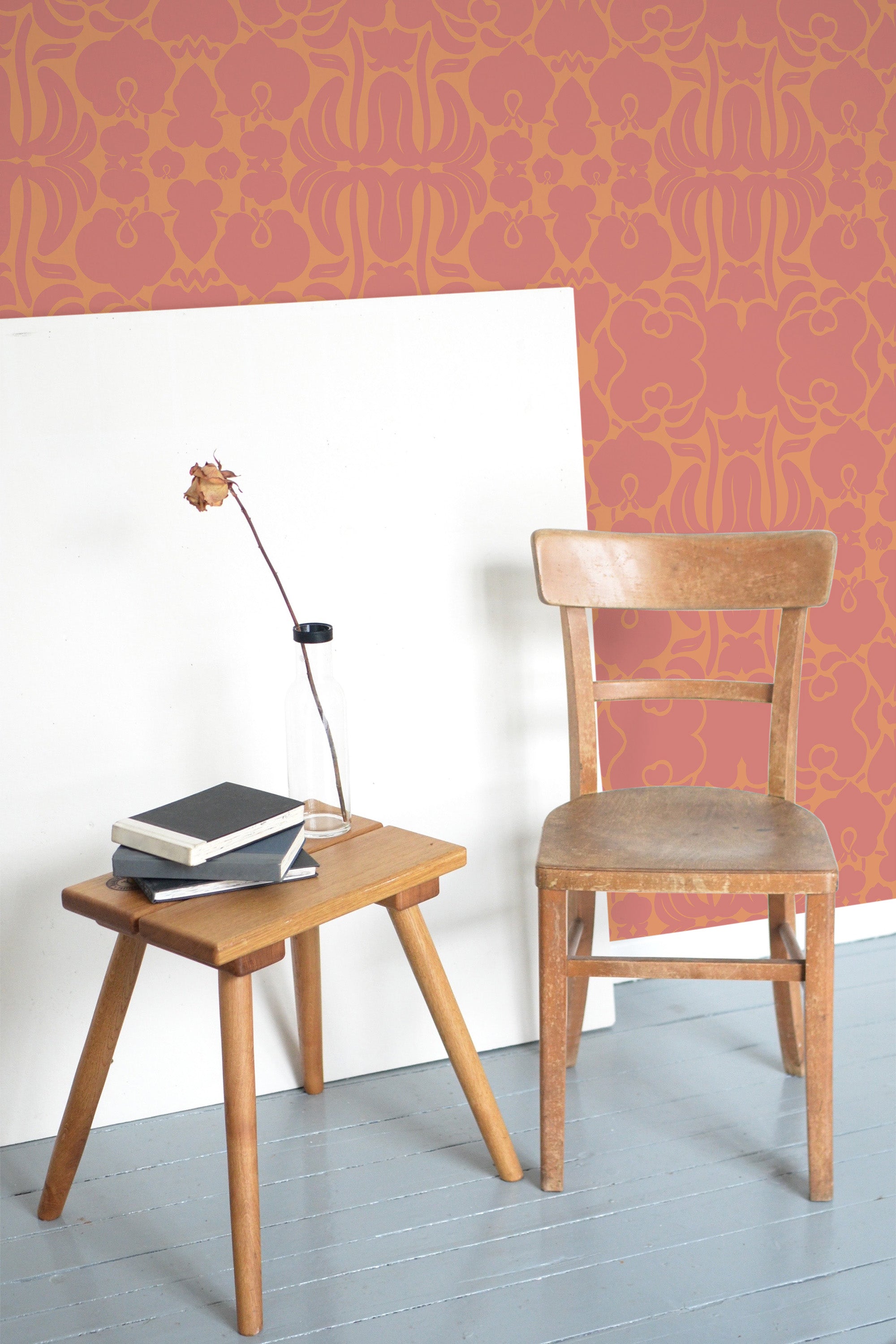 Self-adhesive Victorian flower ornaments wallpaper with intricate floral patterns in a warm orange hue on a room wall, complemented by wooden furniture.