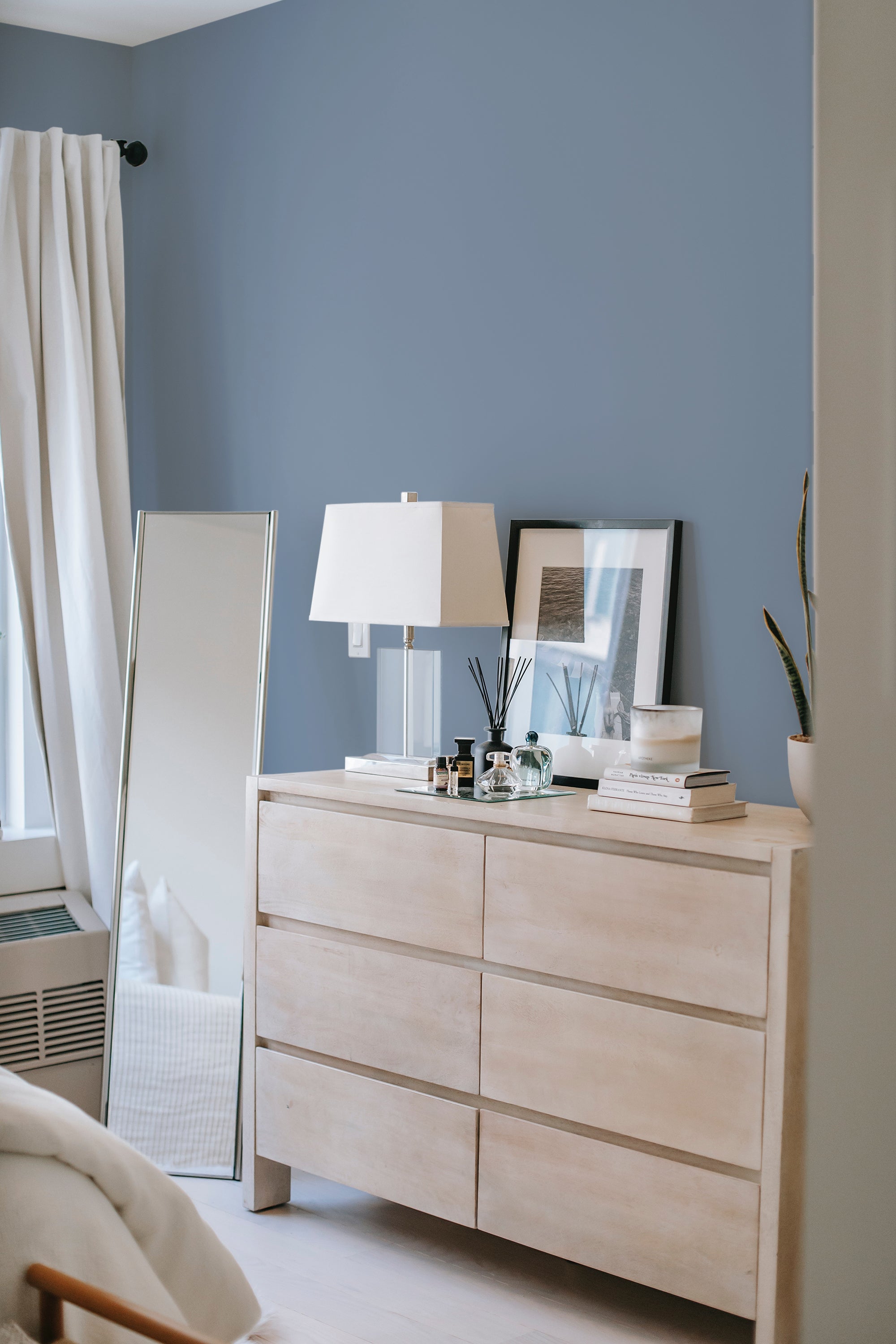 A room with a solid dusty blue wallpaper covering the wall, creating a calm and serene ambiance. Traditional wallpaper.