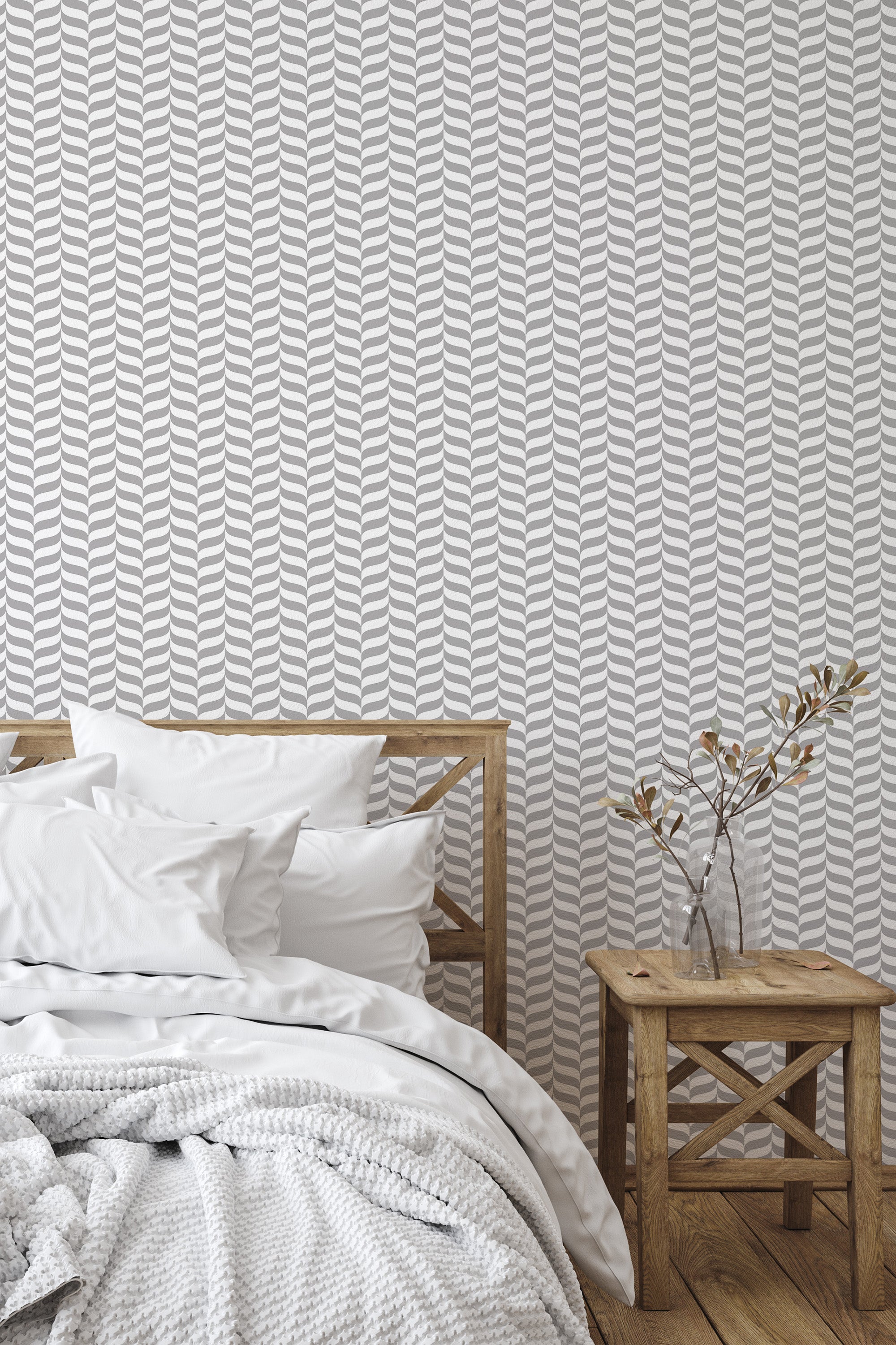 Self-adhesive Elegant Gray Herringbone wallpaper on a bedroom wall behind a bed with white bedding and a wooden bedside table with a vase.
