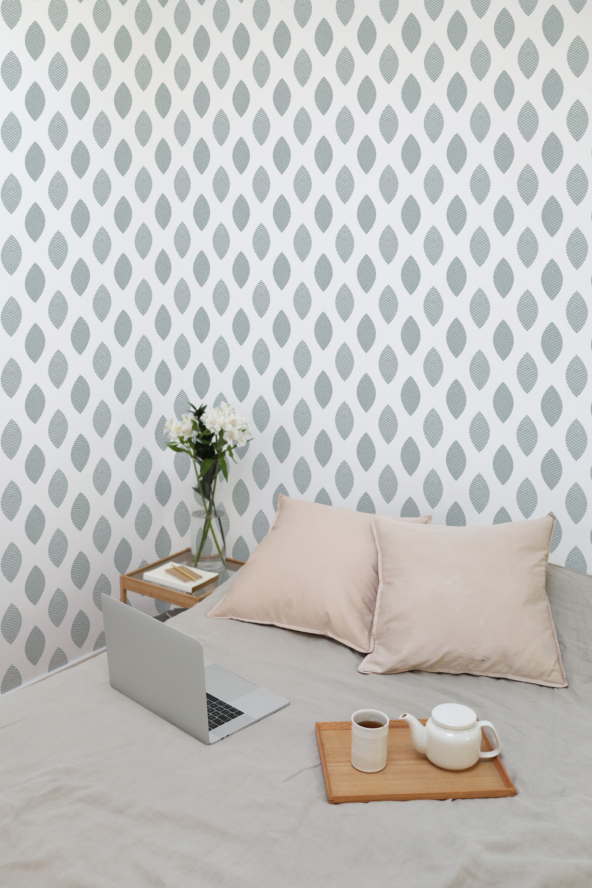 Self-adhesive wallpaper with a geometric pattern of evenly spaced, vertical leaf-shaped lines in soft gray on a white background, creating a modern yet subtle accent wall in the room.