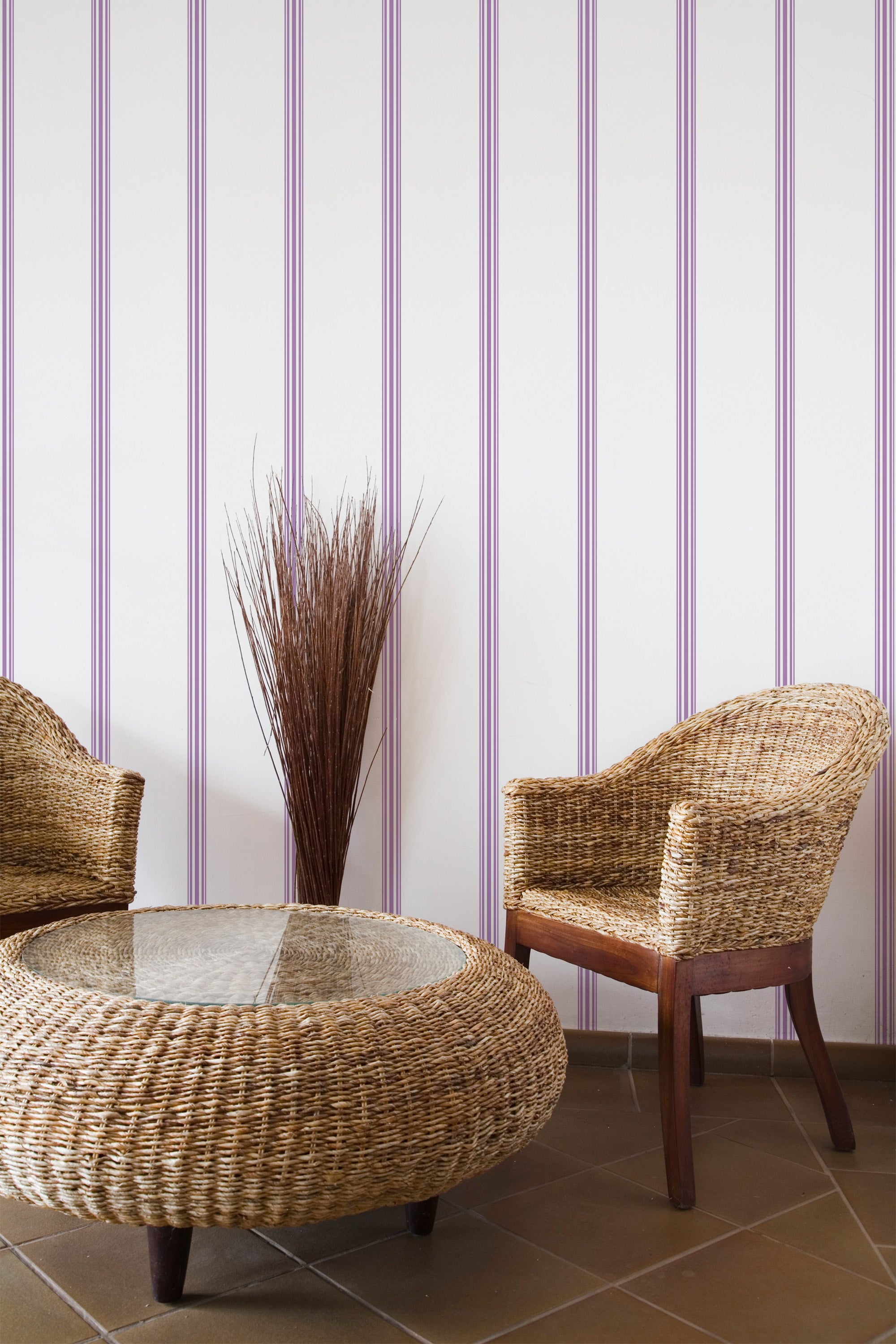 Self-adhesive wallpaper with vertical purple stripes in alternating shades on a light background, complementing a cozy, earthy-themed room with wicker furniture and a minimalistic d��cor setup.