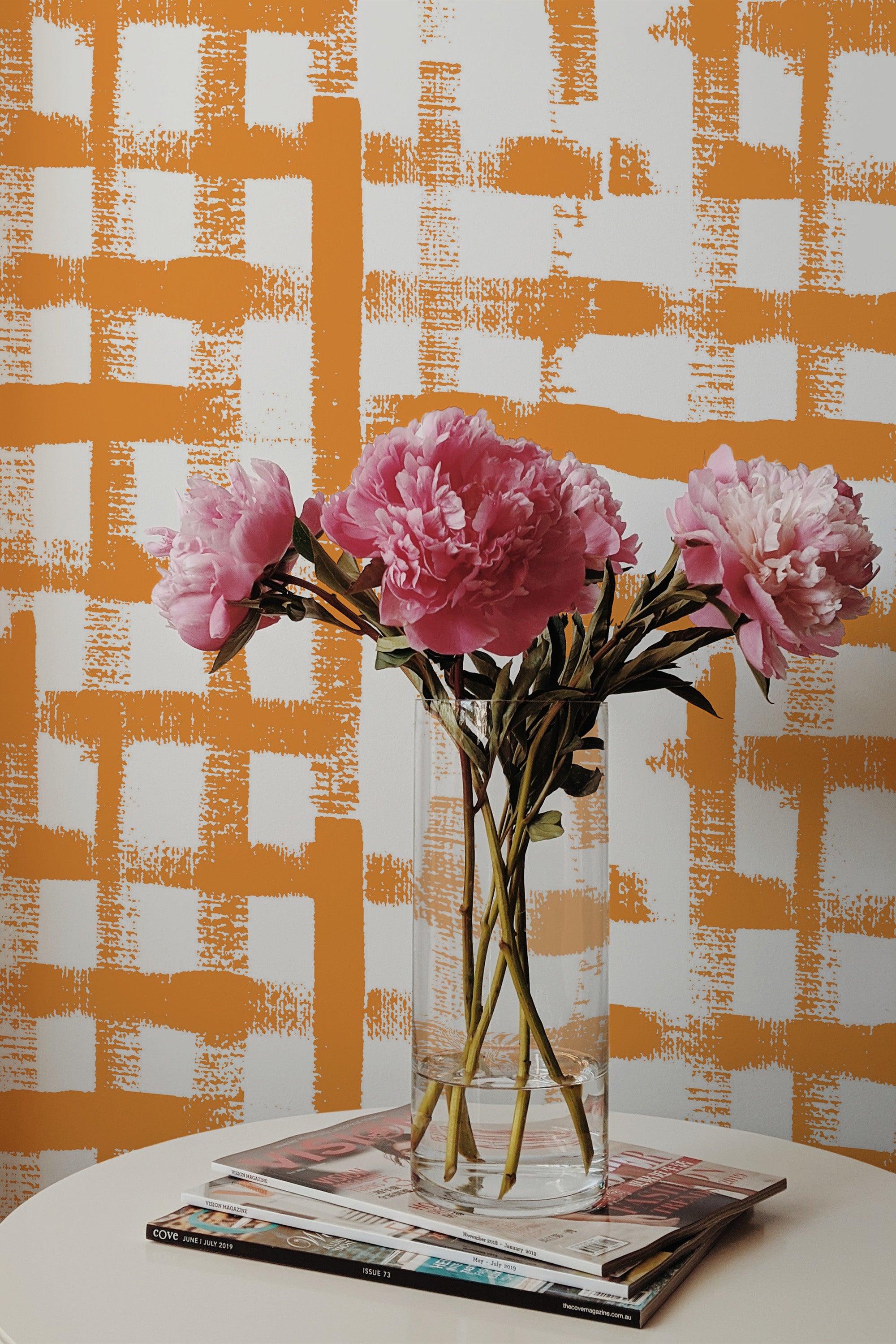 Self-adhesive wallpaper with a vibrant brush grid design in warm orange tones on a white background.