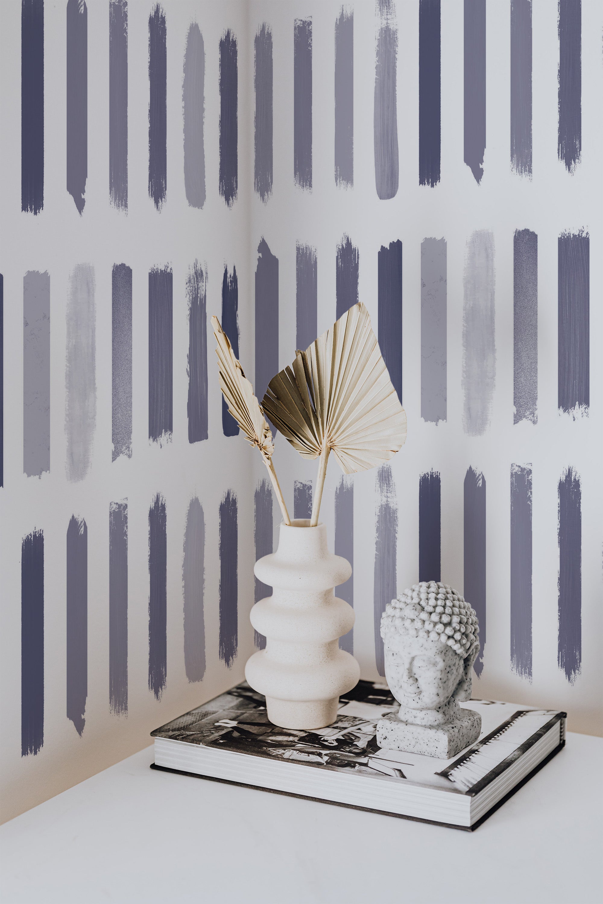 Self-adhesive wallpaper with a Brush design of vertical, paintbrush-like strokes in varying shades of grey, blue, and soft purple, creating a modern, artistic look.