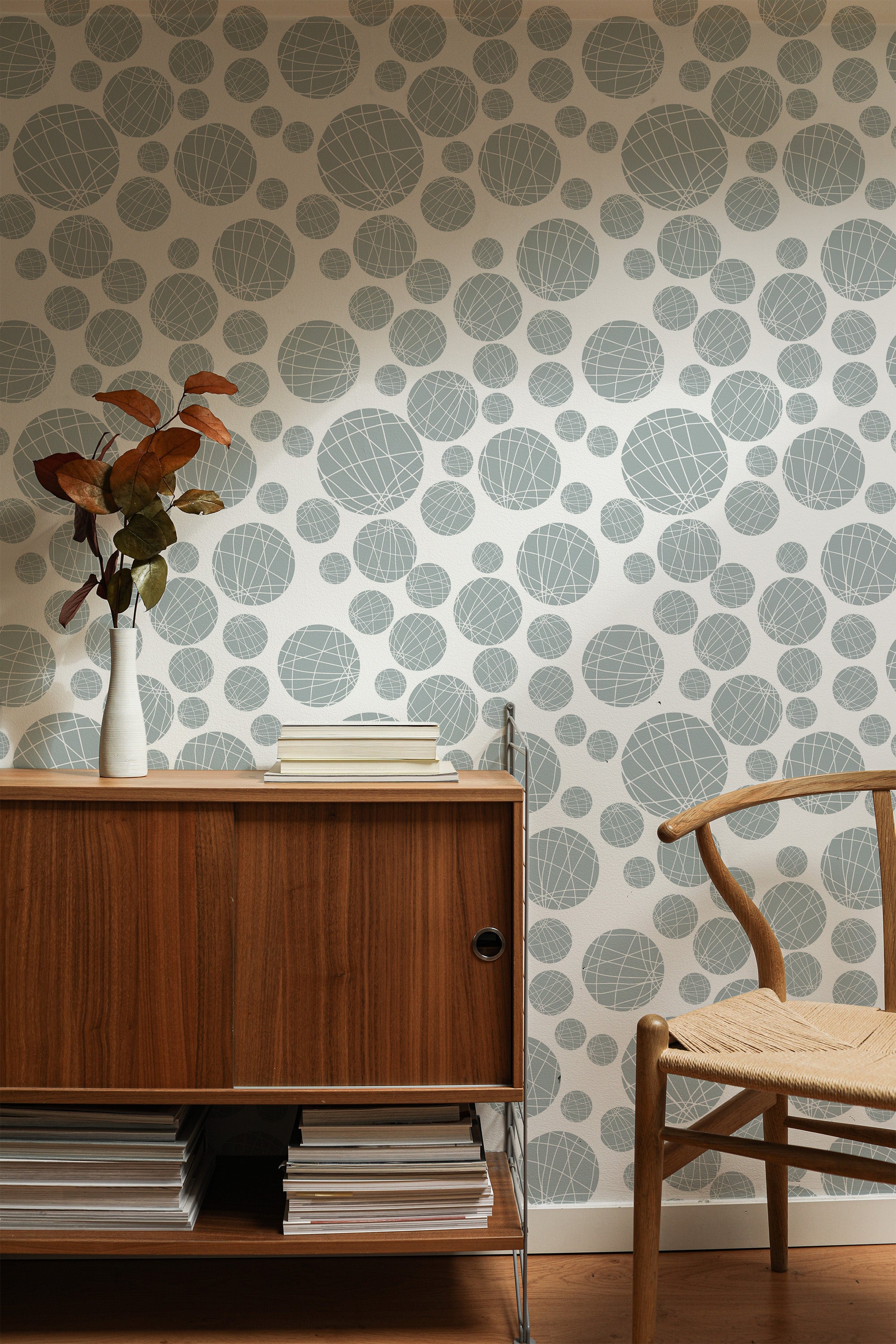 Self-adhesive wallpaper with a seamless circle design in various sizes, combining shades of gray and blue on an off-white background.