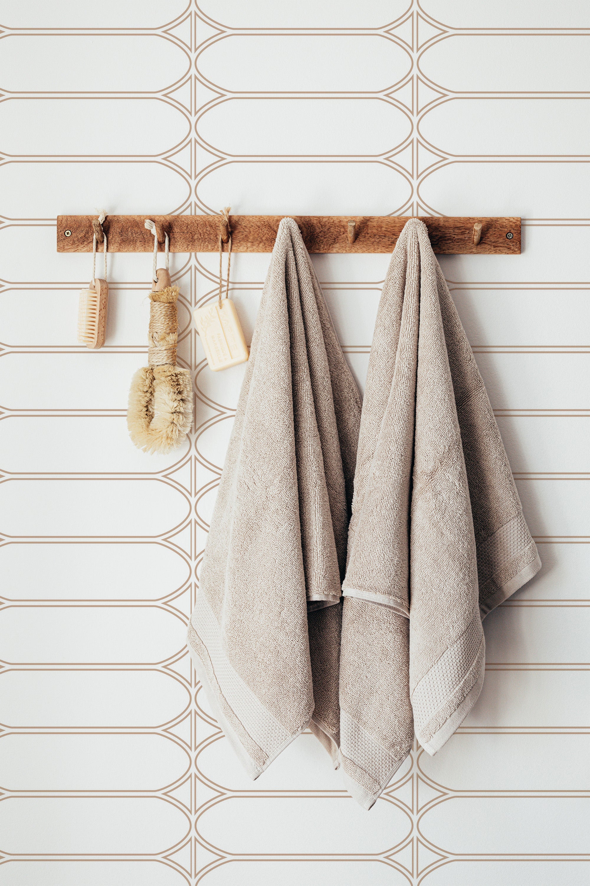 Self-adhesive wallpaper with a white background and browny-gold geometric pattern of ovals and horizontal lines, adding a minimalistic and modern touch to the room.